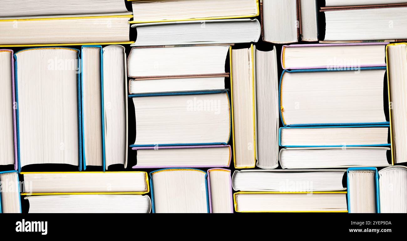 Una disposizione di libri in copertina rigida con spine vibranti crea uno schema visivamente accattivante, simboleggiando la conoscenza e l'istruzione. Perfetto per la biblioteca Foto Stock
