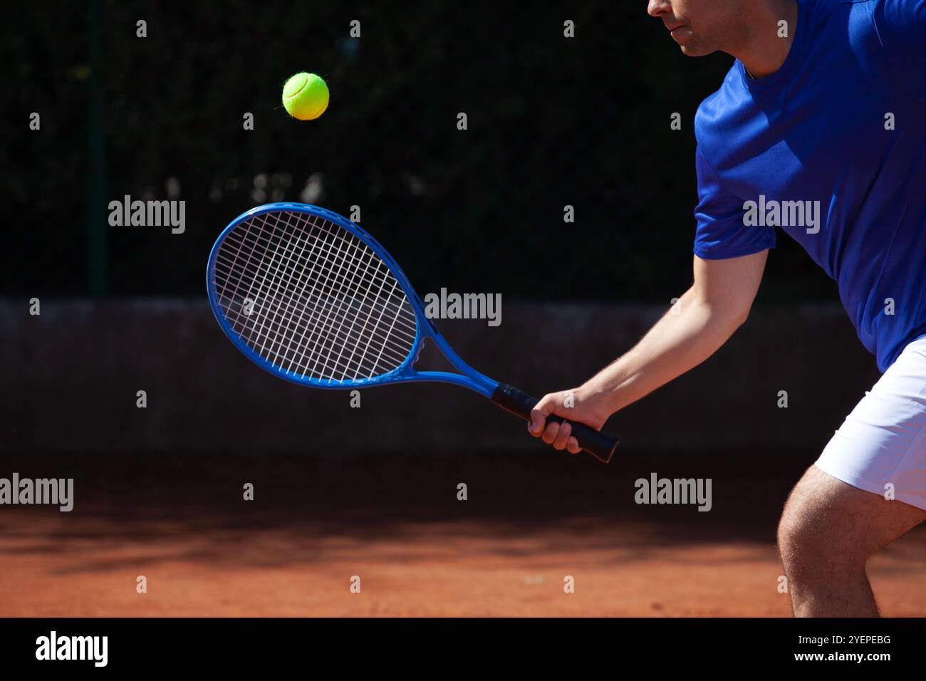 Il tennista professionista incontra una palla colpita dall'avversario su un campo di gioco in argilla Foto Stock