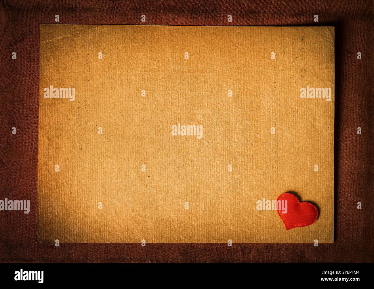 Foto di vignettatura della forma del cuore rosso sul primo piano della carta vecchia Foto Stock