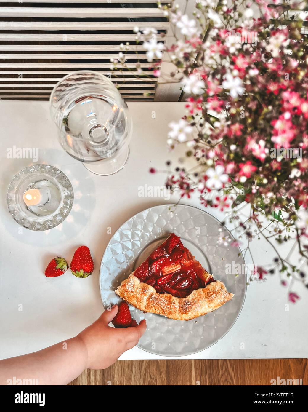 La mano del ragazzo raggiunge un pezzo di torta di fragole Foto Stock La mano del ragazzo raggiunge un pezzo di torta di fragole Foto Stock