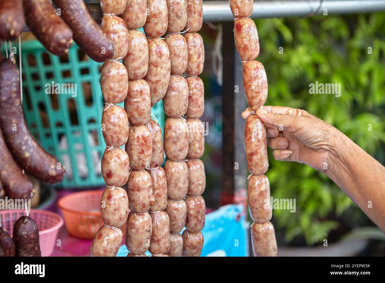 La scelta di una mano anziana acquista salsiccia di manzo Thai i-san Foto Stock