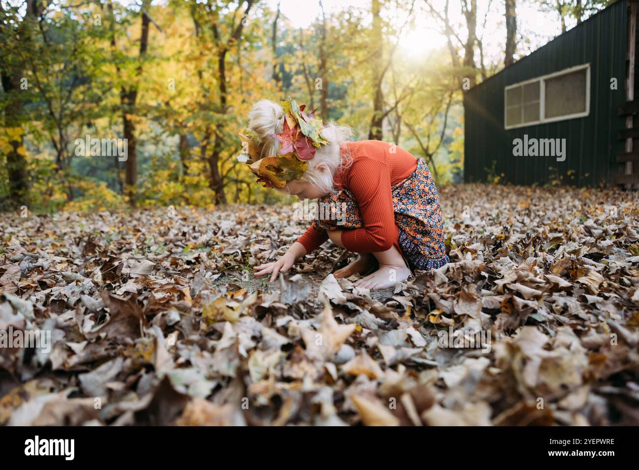 Bambino vestito con stravaganti abiti autunnali che giocano con le foglie Foto Stock