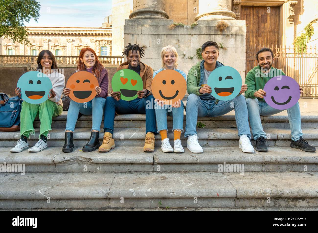 Amici multiculturali che esprimono emozioni sui social media con volti emoji all'aperto Foto Stock