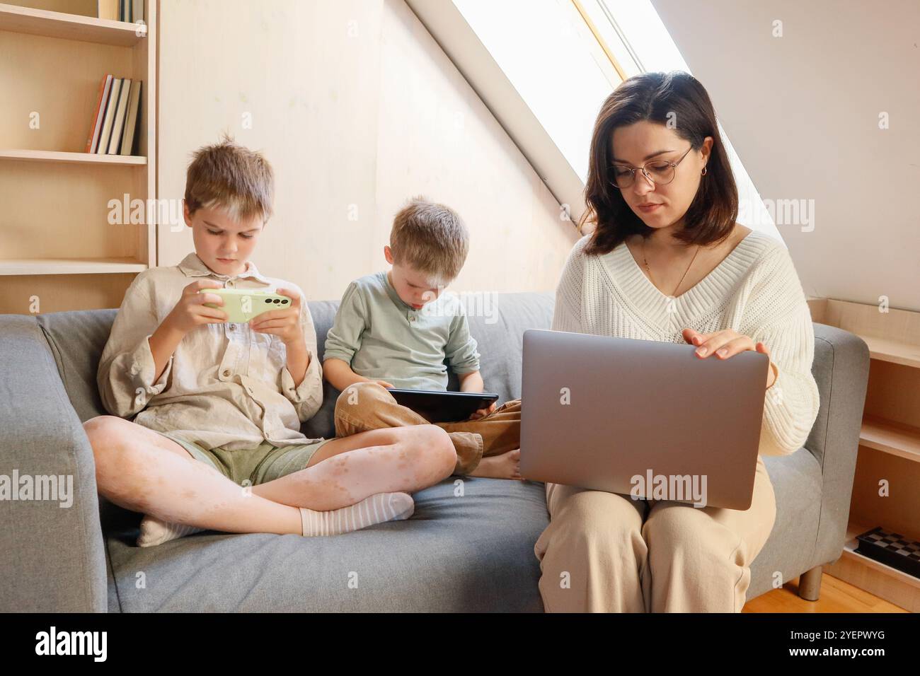 Tempo di visualizzazione di una madre e dei suoi figli che lavorano con un notebook Foto Stock