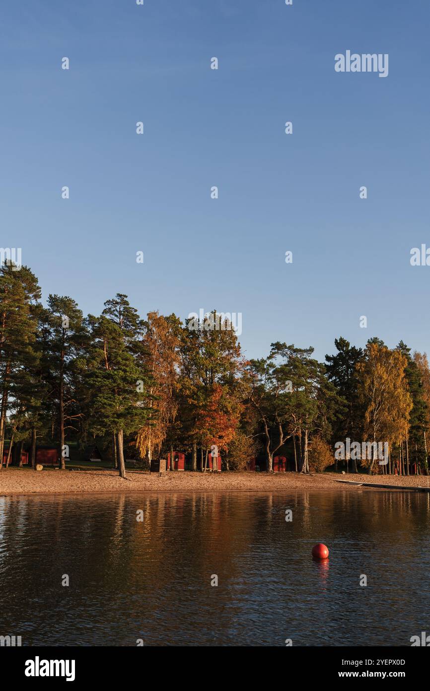 Edificio rosso nascosto dietro gli alberi vicino alla costa del lago Foto Stock