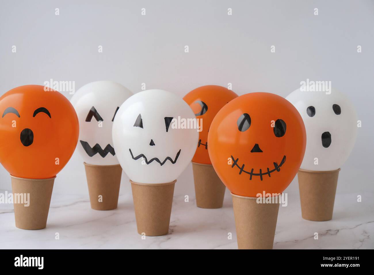 La faccia di Jack dipinta sulle bollature. Preparazione di palline bianche e arancioni fai da te per la festa di Halloween. Halloween attività a casa. Giocattoli fatti a mano Artigianato per bambini Foto Stock