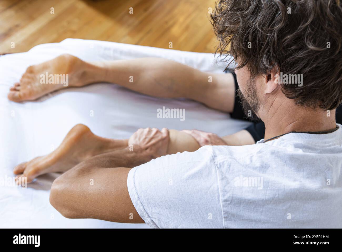 Uomo che massaggia un piede. Giovane uomo con massaggio ai piedi in una clinica di fisioterapia. Massaggio sportivo. Sano trattamento di ferita di sport Foto Stock