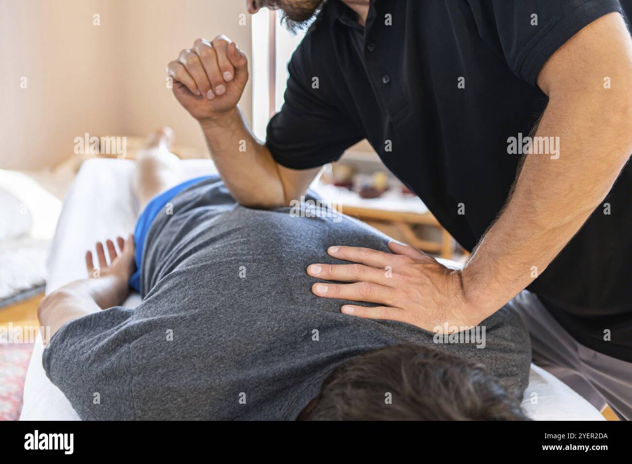 Massaggio sportivo maschile terapista applicando pressione a un cliente utilizzando avambraccio e peso corporeo. Osteopatia e concetti di riabilitazione delle lesioni sportive Foto Stock