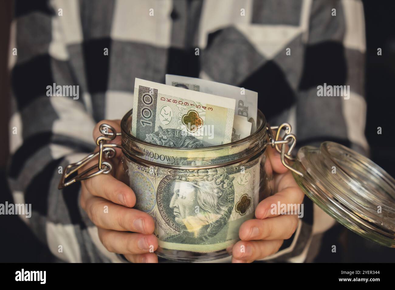 Banconota polacca zloty risparmio denaro in vaso di vetro. Donna irriconoscibile consumo moderato ed economia raccogliere denaro. Suggerimenti. Business, finanza, savi Foto Stock