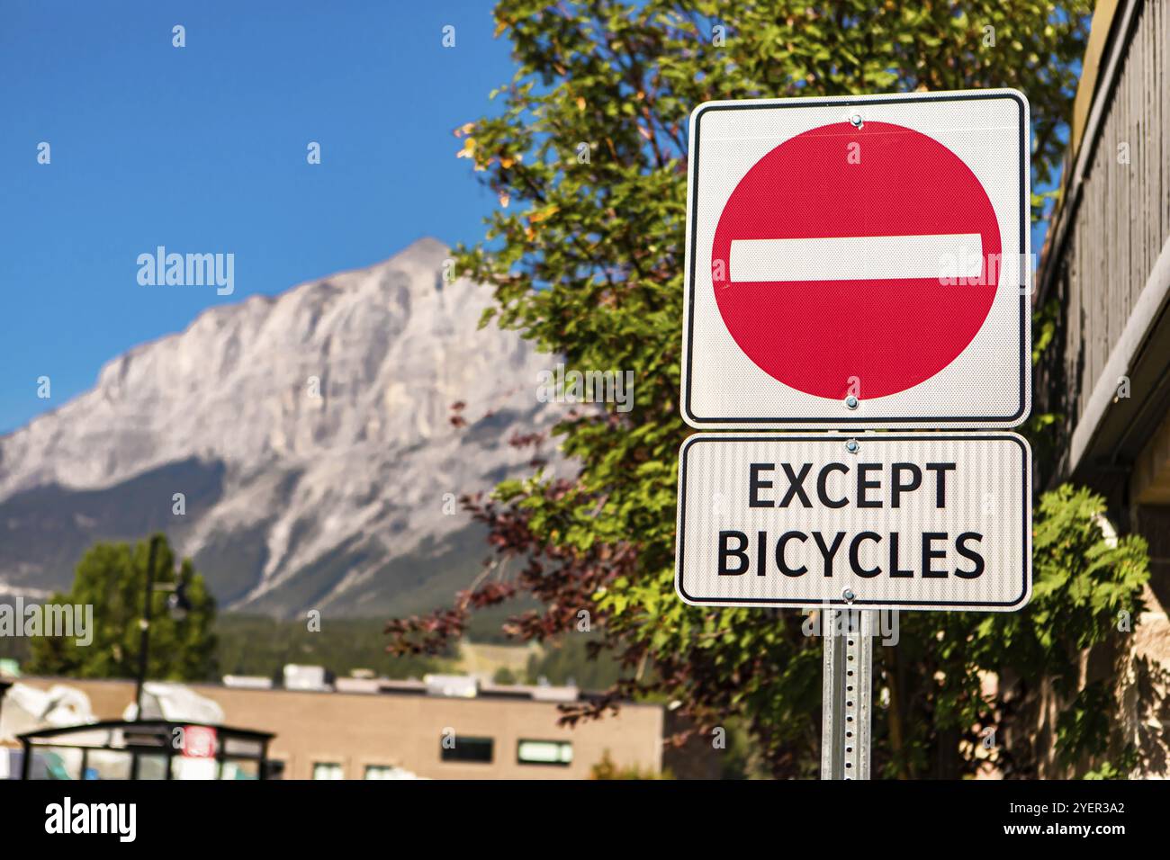 Attenzione selettiva: Non entrare nel cartello stradale con tranne il cartello per le biciclette, contro edifici e montagne e il cielo blu, British Columbia, Canada, Nord Foto Stock