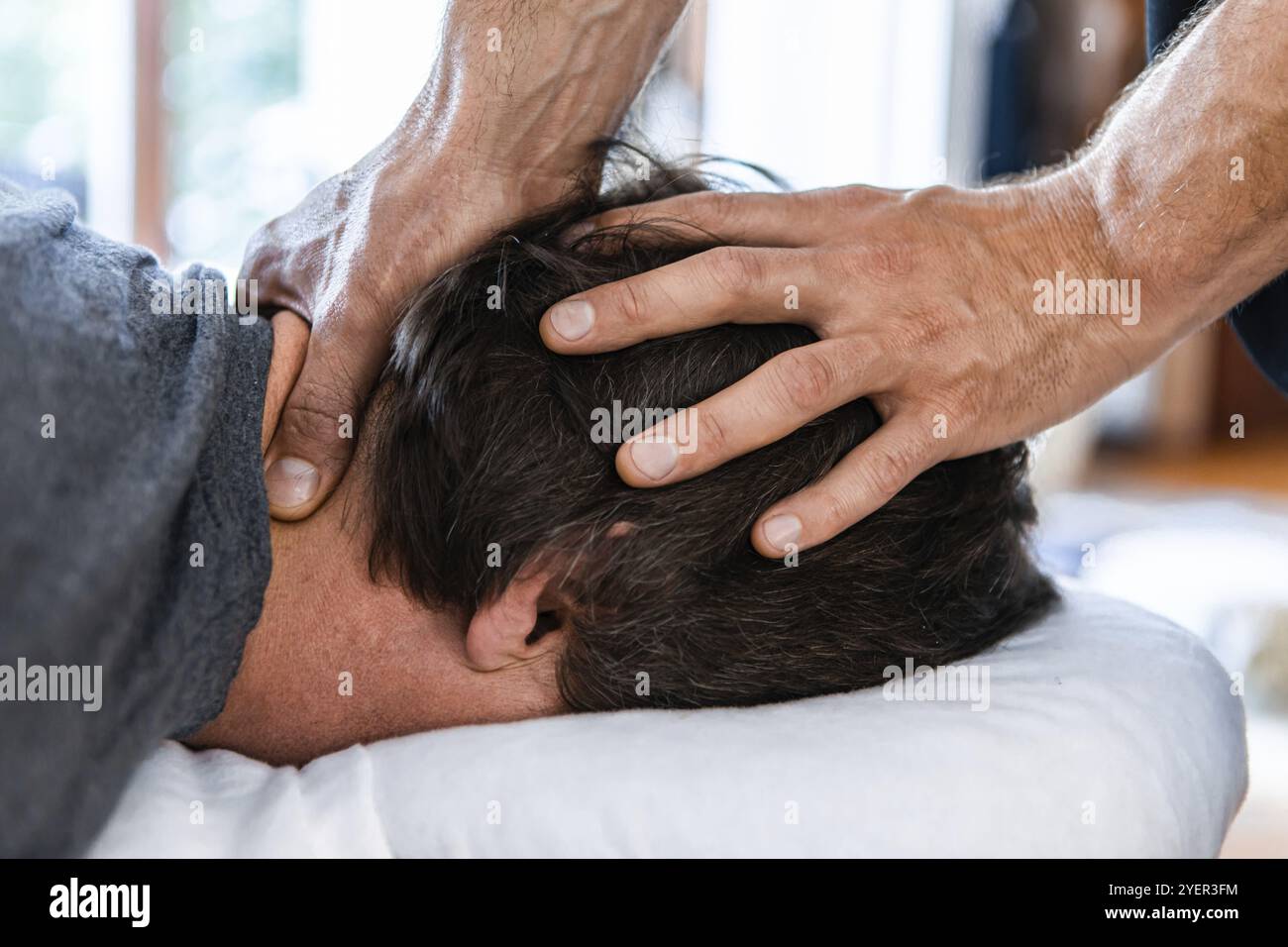 Un massaggiatore sportivo maschile che effettua massaggio alla testa e al collo. Trattamento terapeutico di massaggio del corpo. Osteopatia e riabilitazione delle lesioni sportive Foto Stock