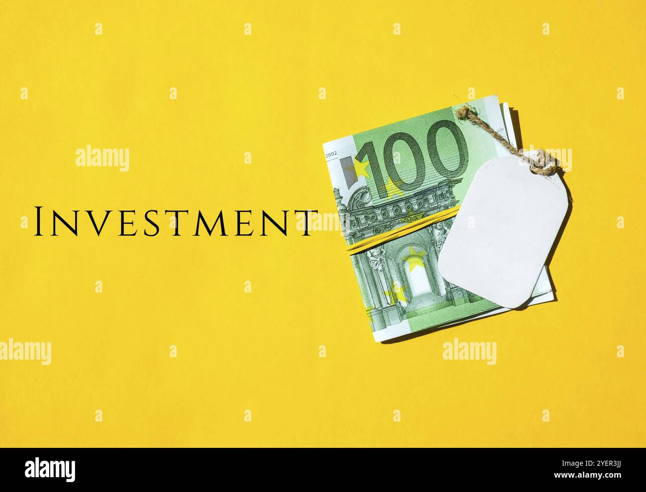 Euro denaro contante in elastico, testo di nota INVESTIMENTO scritto, concetto di mentalità per il costruttore di ricchezza, ricordarsi di impostare una piccola quantità di denaro per investire un Foto Stock