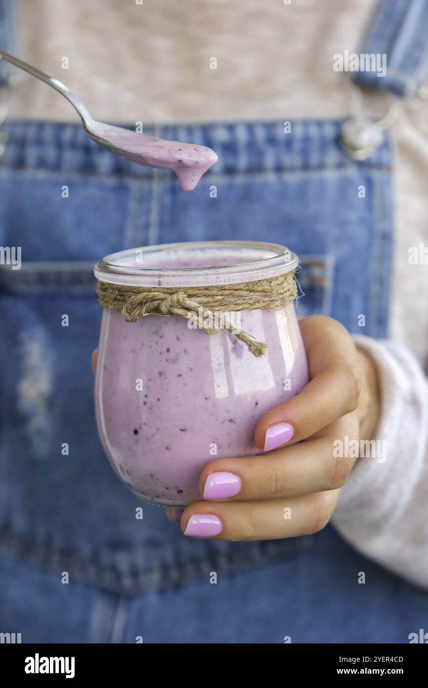 Mani femminili che tengono frullato mirtillo con mirtilli. Donna che mangia un bicchiere di prima colazione proteina frullato bevanda fatta da purea crudo blueberri Foto Stock