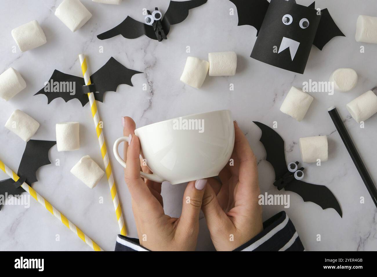Le mani femminili dipingono sui jack di paura della tazza bianca faccia DIY per i capretti Halloween domestico attività di festa arte bambini mestiere decorazioni fatte a mano. Passo dopo passo Foto Stock
