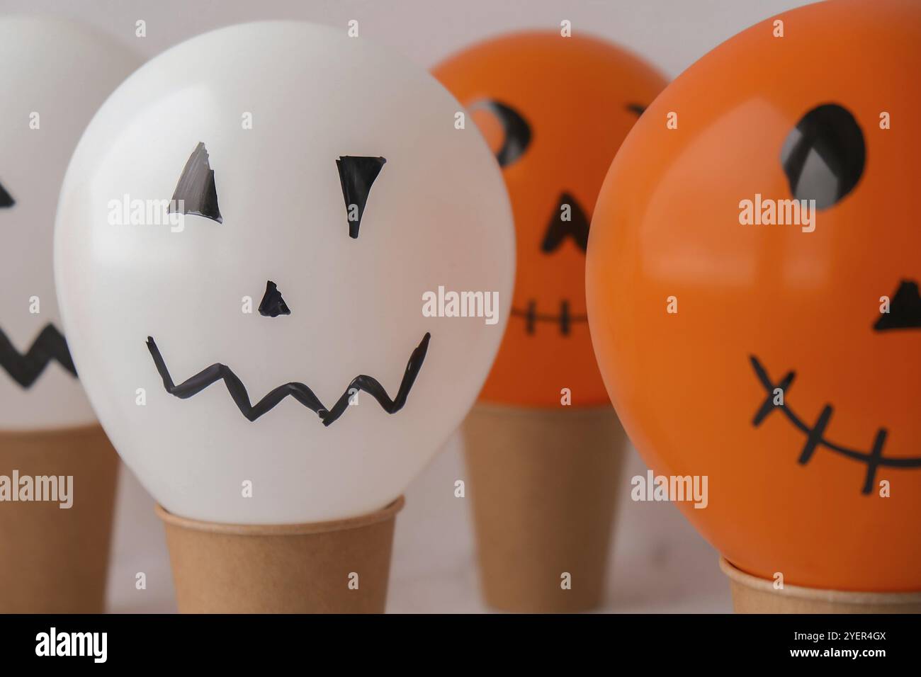 La faccia di Jack dipinta sulle bollature. Preparazione di palline bianche e arancioni fai da te per la festa di Halloween. Halloween attività a casa. Giocattoli fatti a mano Artigianato per bambini Foto Stock