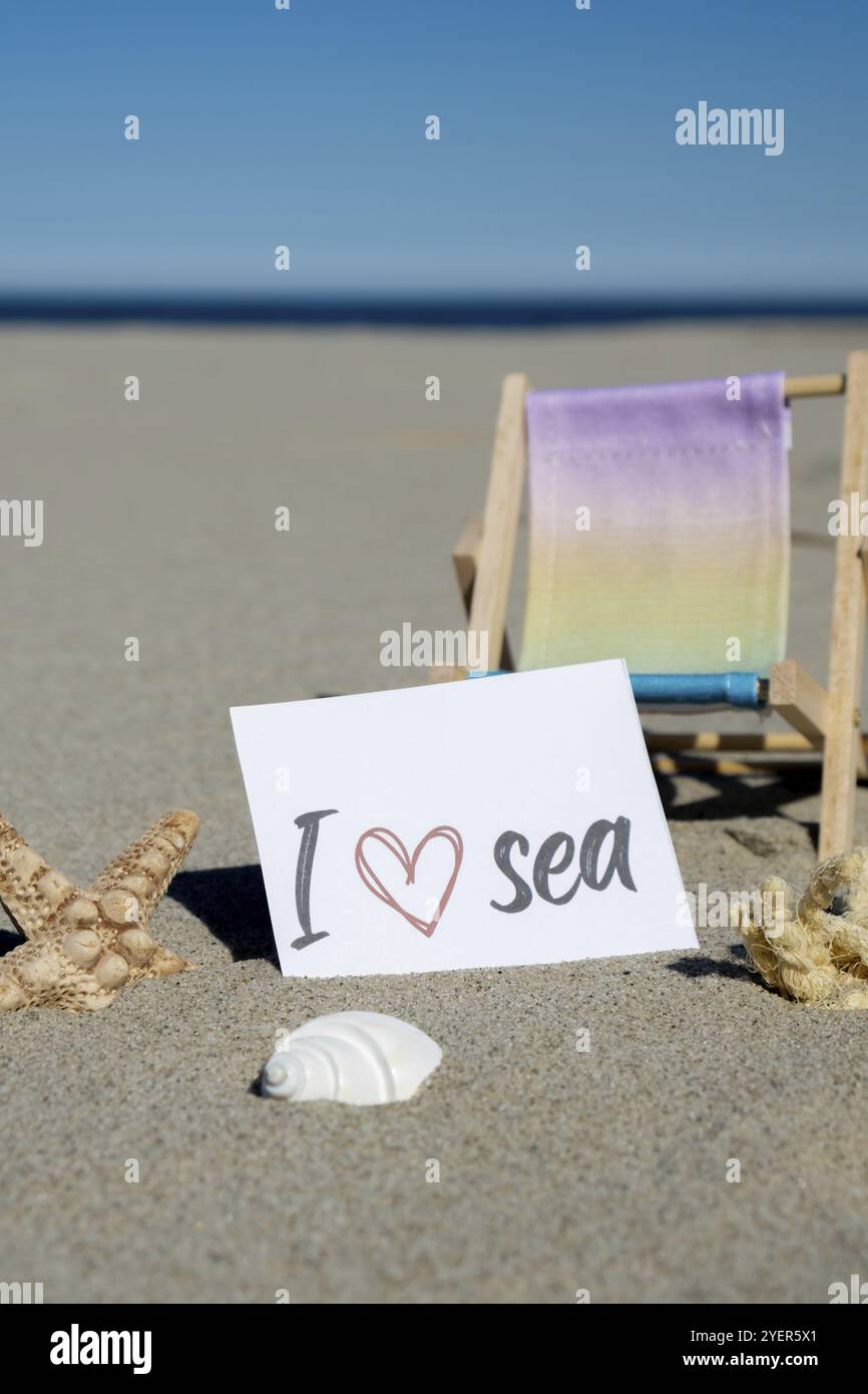 ADORO il testo DEL MARE su carta del biglietto di auguri sullo sfondo della sdraio sulla spiaggia, stelle marine, arredamento per le vacanze estive. Spiaggia sabbiosa, costa soleggiata. Post sul concetto di vacanza Foto Stock