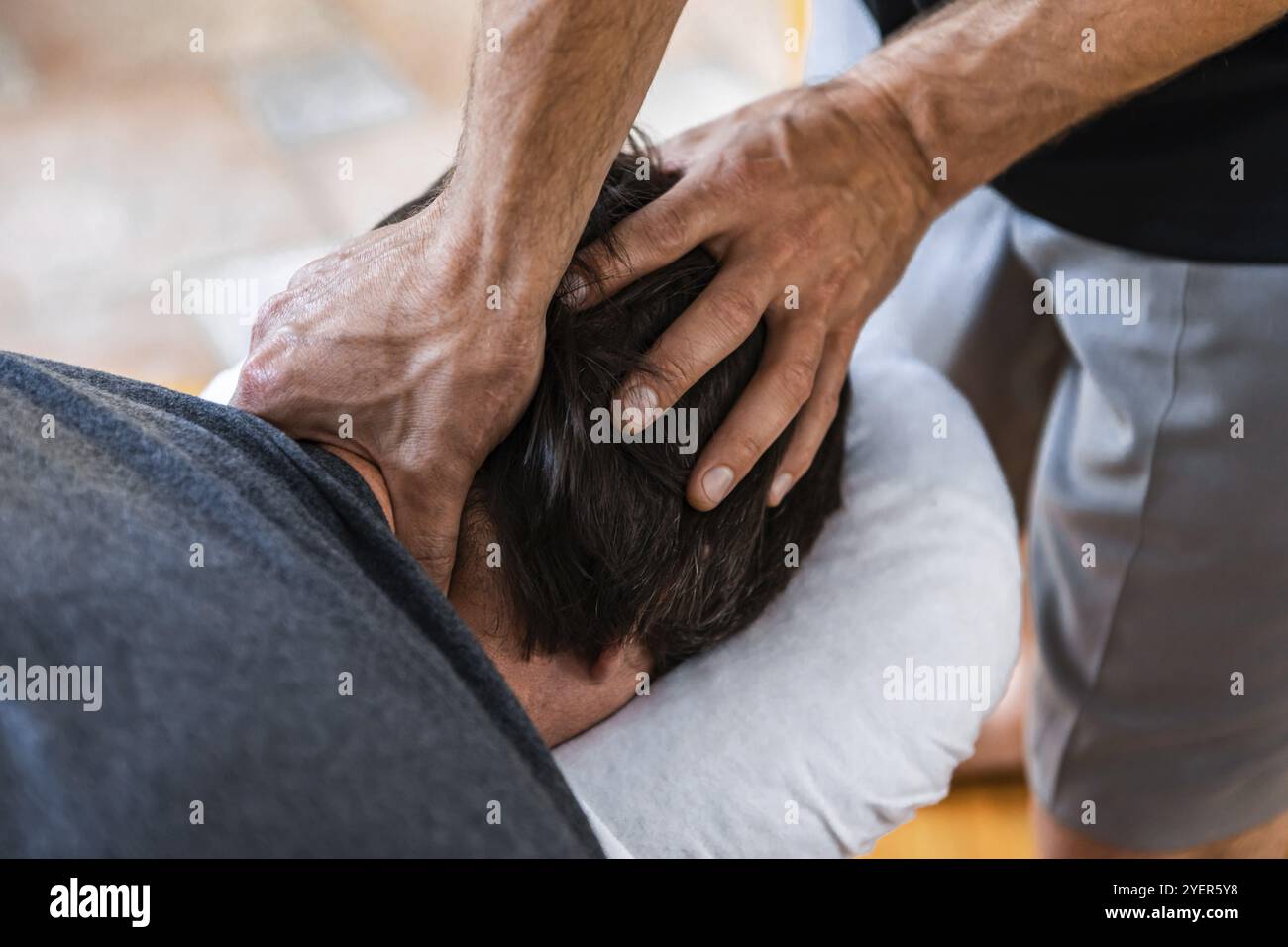 Un giovane uomo sul trattamento benessere massaggio sportivo. Un massaggiatore sportivo maschile che effettua massaggio alla testa e al collo. Uno sportivo che gode di un massaggio Foto Stock