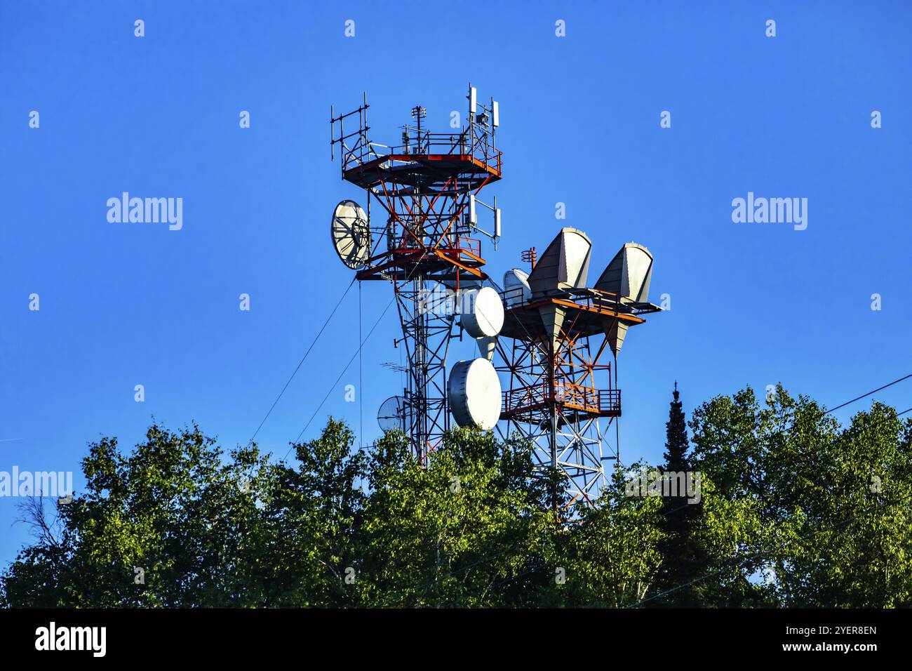 Un basso angolo di visione di un sito di cella tower alloggiata su un cavo alloggiato in acciaio pilone a traliccio, antenna a microonde per 3G, 4G, 5G il trasferimento dei dati e il segnale boost Foto Stock