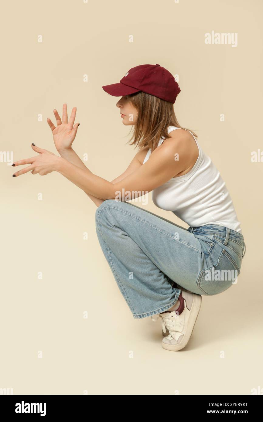 Serie di foto in studio di donna in classico abito base - jeans blu e canotta bianca e cappellino rosso da baseball Foto Stock