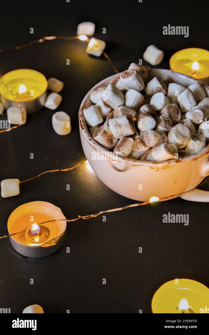 Tazza con cacao invernale caldo e marshmallow di notte. Luci di Natale. Candele a lume di tè. Buona notte, dolci sogni. Giornate invernali accoglienti. Hygge Foto Stock