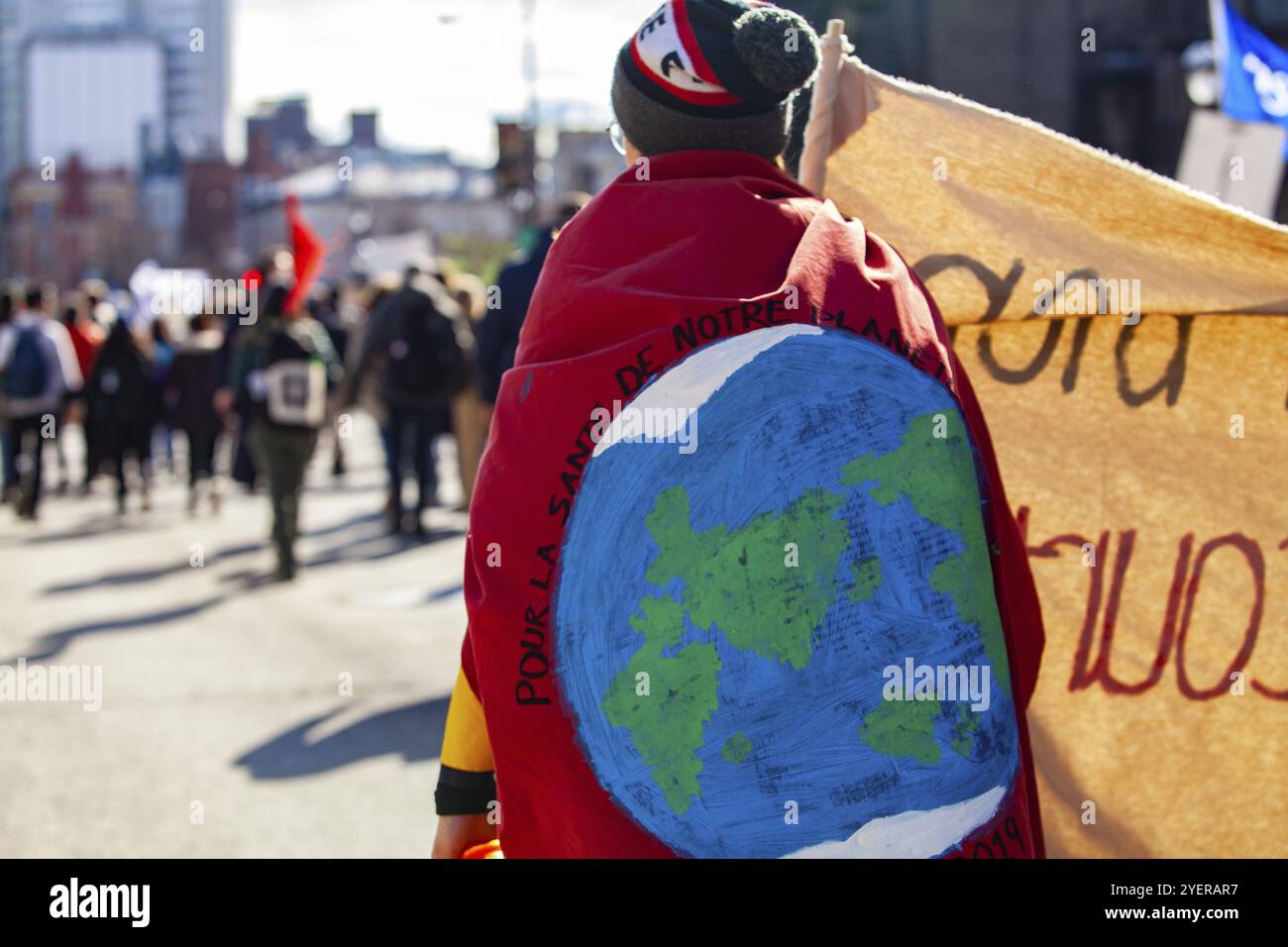 Un dimostratore ambientale viene visto da dietro, in marcia su una strada affollata con durante una manifestazione contro il cambiamento climatico Foto Stock