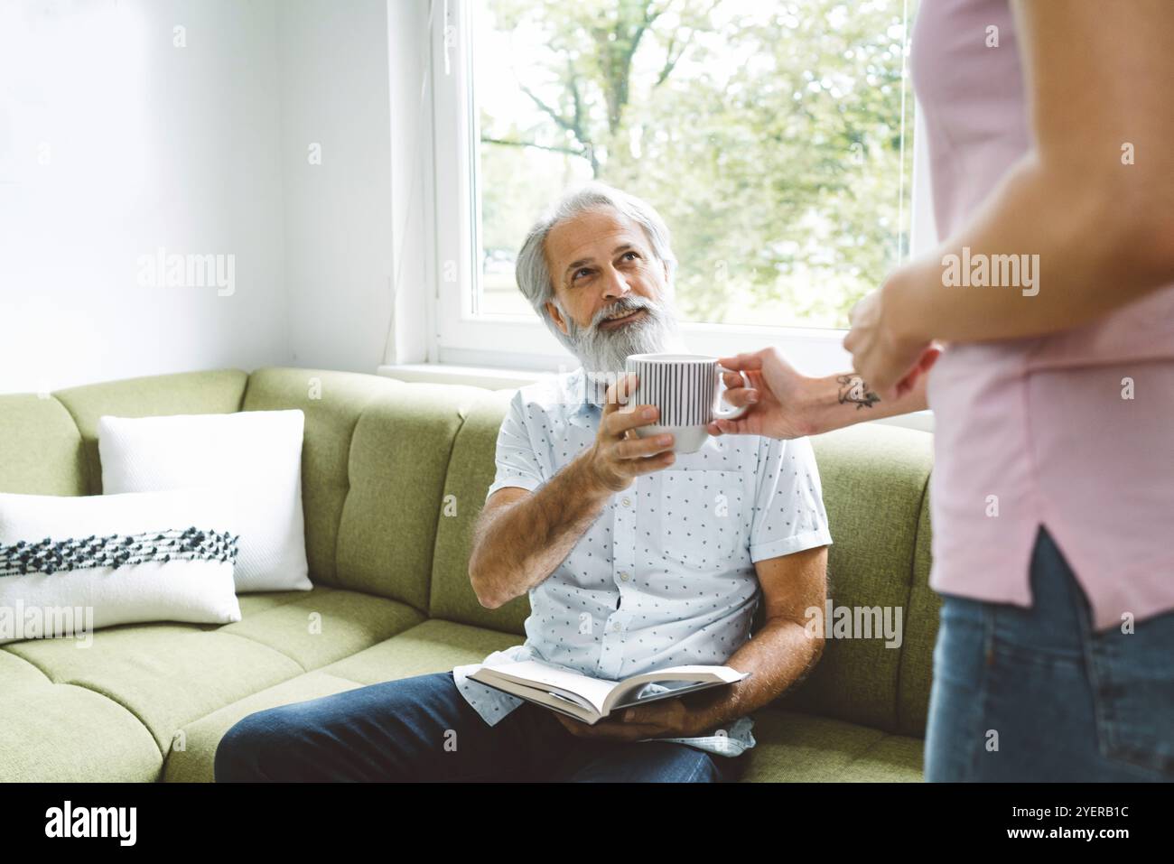 Giovane donna caucasica che si prende cura di suo nonno, uomo anziano con barba e capelli grigi. Nipote in visita a suo nonno, spendendo qualità ti Foto Stock