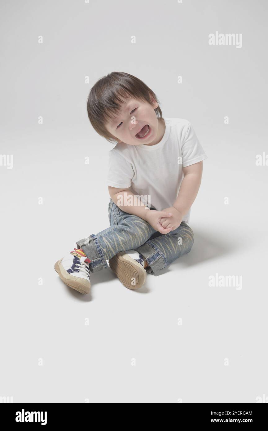 bambino di 2 anni seduto e piangendo Foto Stock