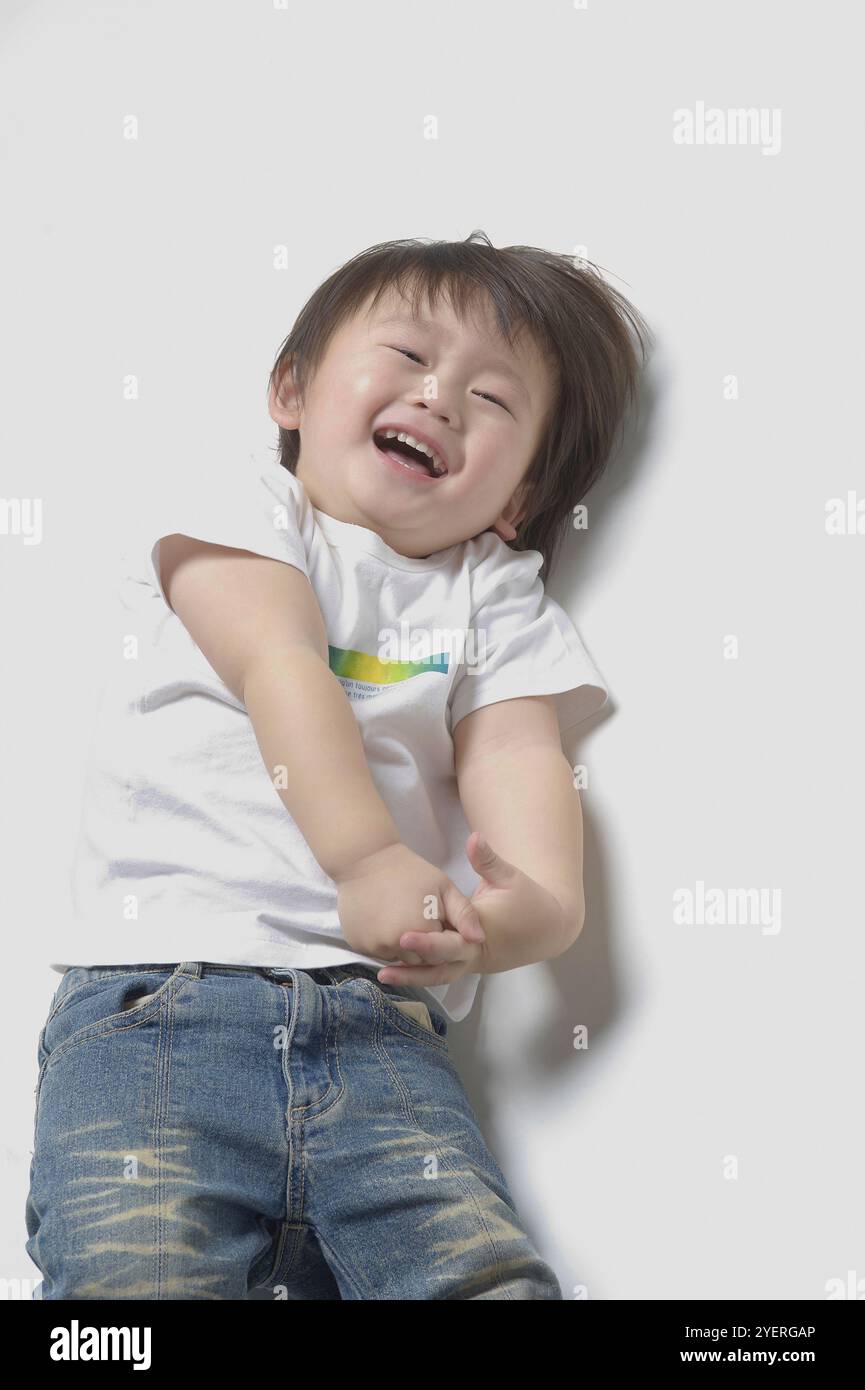 bambino di 2 anni sdraiato e ridendo Foto Stock