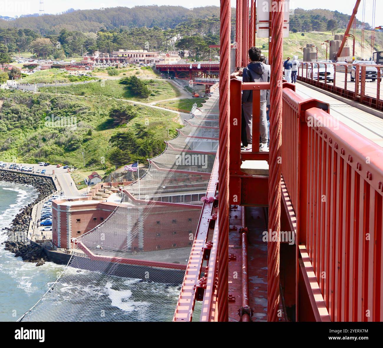 Turisti sul Golden Gate Bridge che guardano sulle reti anti-suicidio e la fortezza dell'epoca della Guerra di secessione americana di Fort Point San Francisco, California, USA Foto Stock