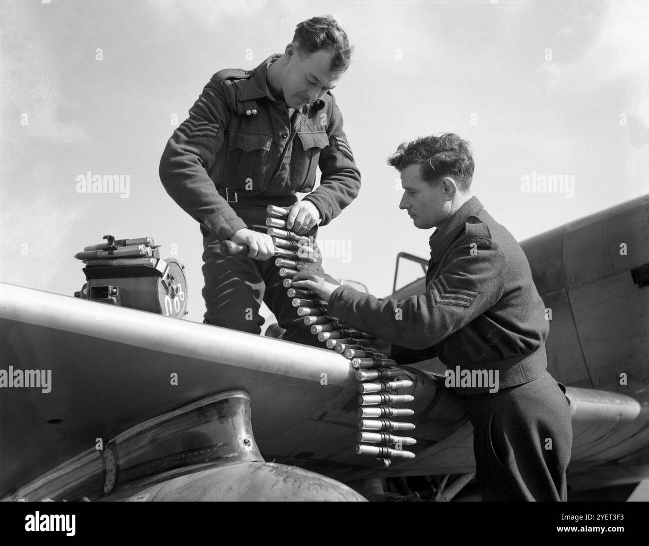 Equipaggio di terra che caricava cinture di munizioni su un Hawker Tempest, un aereo da caccia britannico utilizzato principalmente dalla Royal Air Force (RAF) nella seconda guerra mondiale e uno dei caccia più potenti della seconda guerra mondiale; a bassa quota era il più veloce velivolo monomotore ad elica della guerra. È entrato in servizio nel 1944, ed è stato particolarmente efficace contro la minaccia di bombardamenti volanti V-1, e attacchi a terra che supportavano le principali invasioni come l'operazione Market Garden. Foto Stock