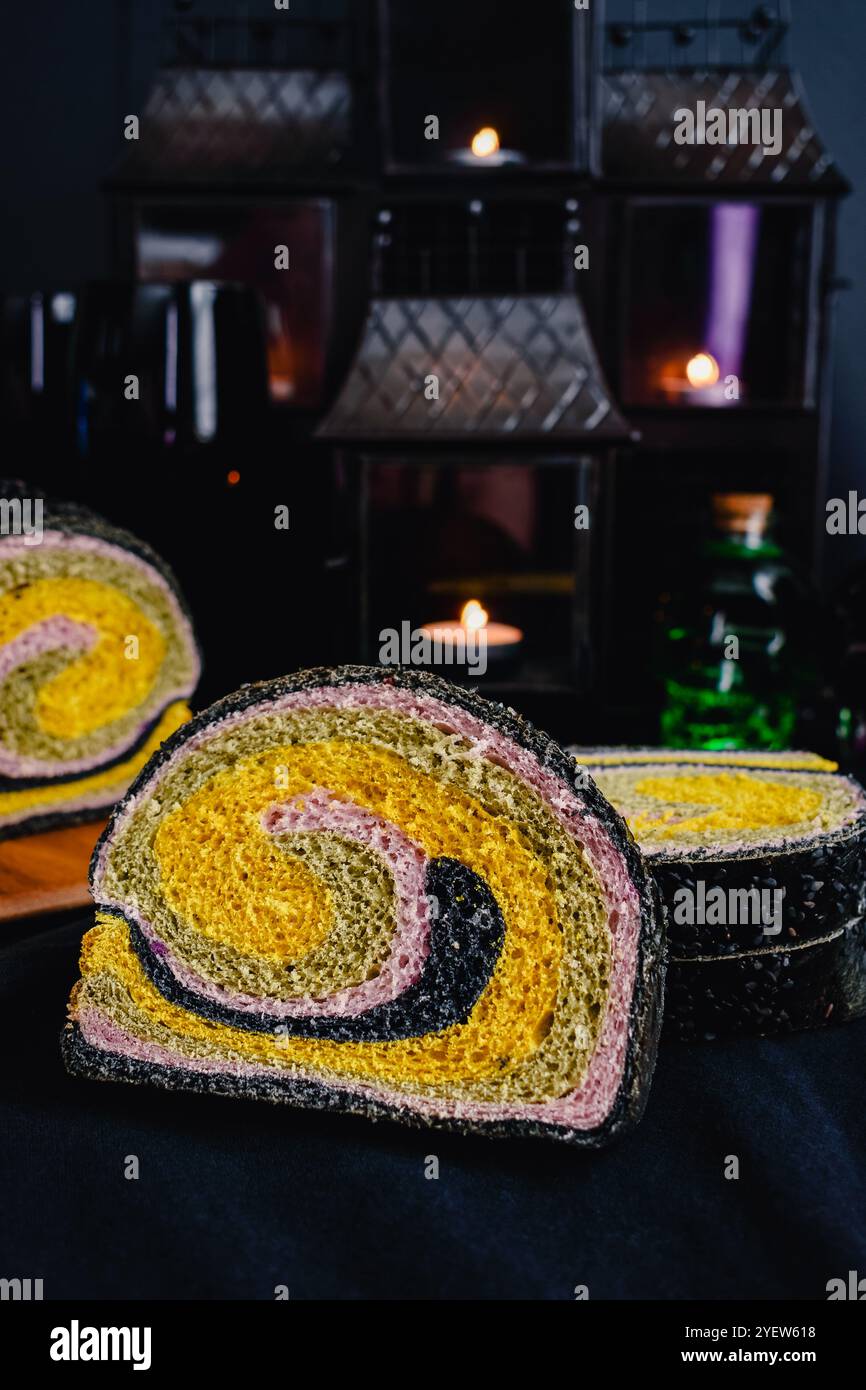 Pane a spirale colorato con tema Halloween: Pane al latte a fette colorato con curcuma, matcha, patate dolci viola e carbone attivo Foto Stock