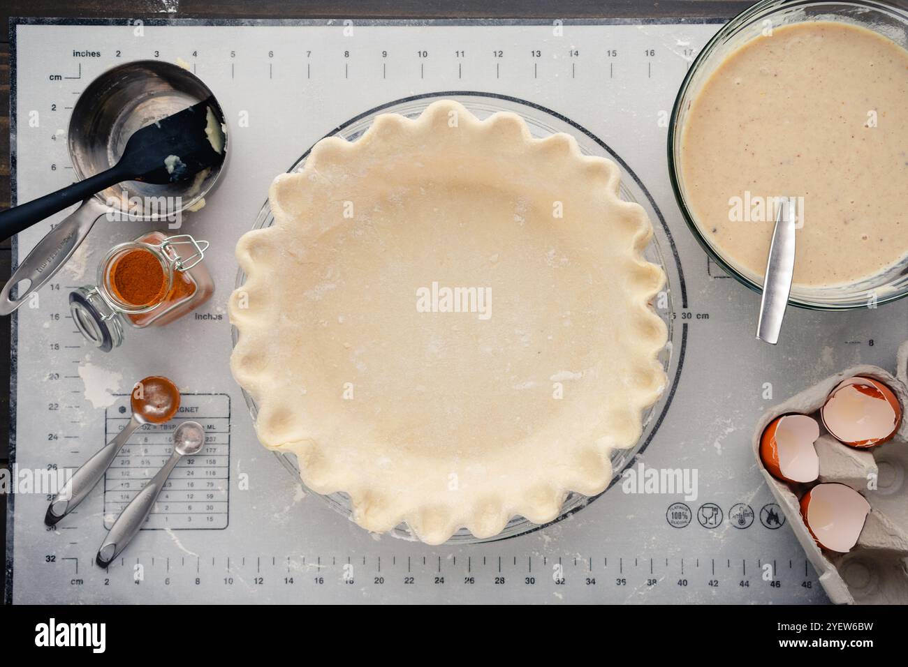 Crosta di torta non cotta con farcitura di torta di zucca bianca nelle vicinanze: Sopra di impasto di torta scanalato nella teglia di vetro con ripieno e attrezzatura a lato Foto Stock