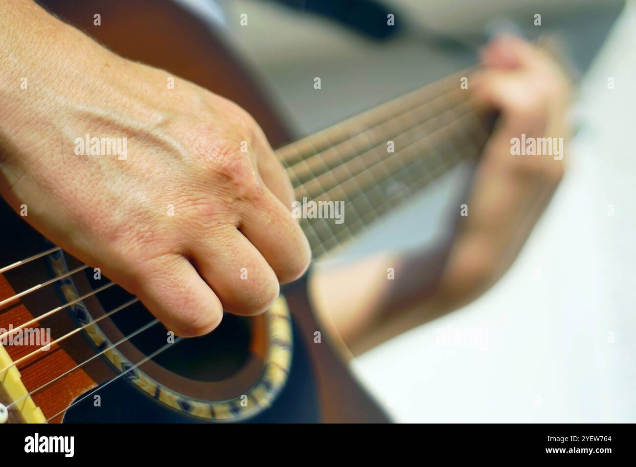 Collo di chitarra con mani maschili che toccano corde metalliche. Uomo che suona la chitarra, foto da vicino. Attività creative: Una persona pratica uno strumento musicale. Foto Stock