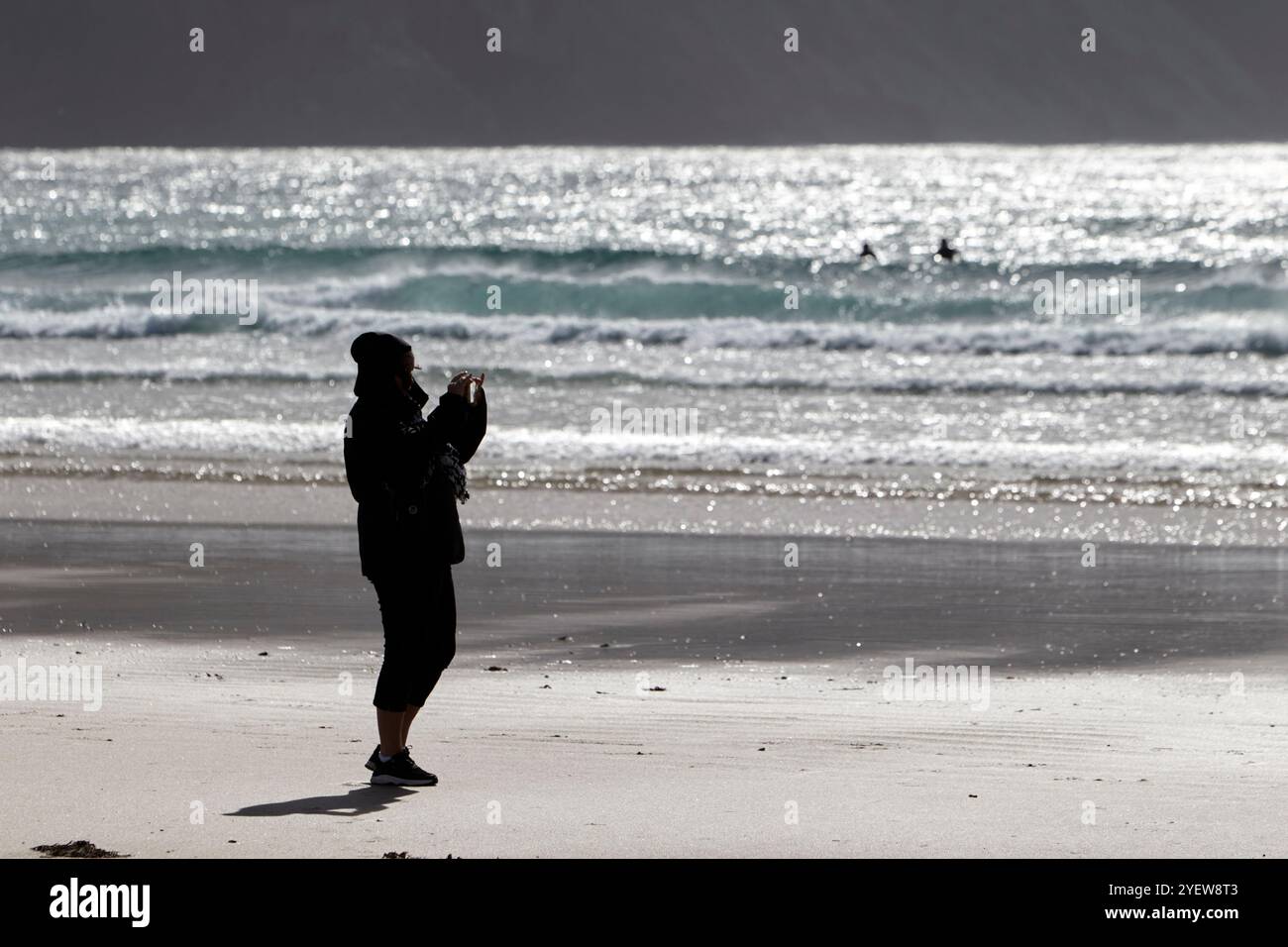 Donna che scatta foto con il telefono sulla spiaggia della chiglia durante l'autunno sull'isola di Achill, contea di mayo, repubblica d'irlanda Foto Stock