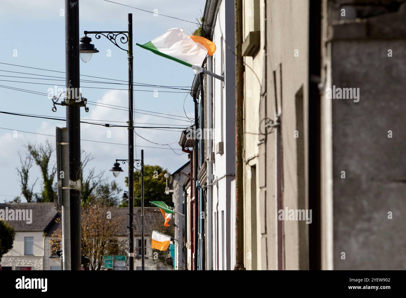 Bandiera irlandese tricolore che batte da case a schiera a Ballinrobe, contea di mayo, repubblica d'irlanda Foto Stock
