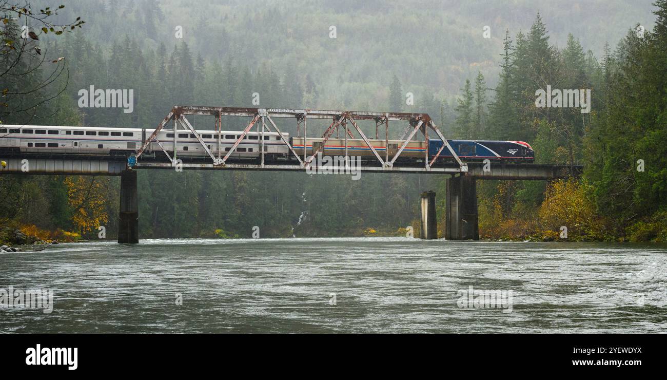 Gold Bar, WA, USA - 28 ottobre 2024; il treno Amtrak Empire Builder da Chicago a Seattle attraversa Big Eddy sotto la pioggia battente Foto Stock