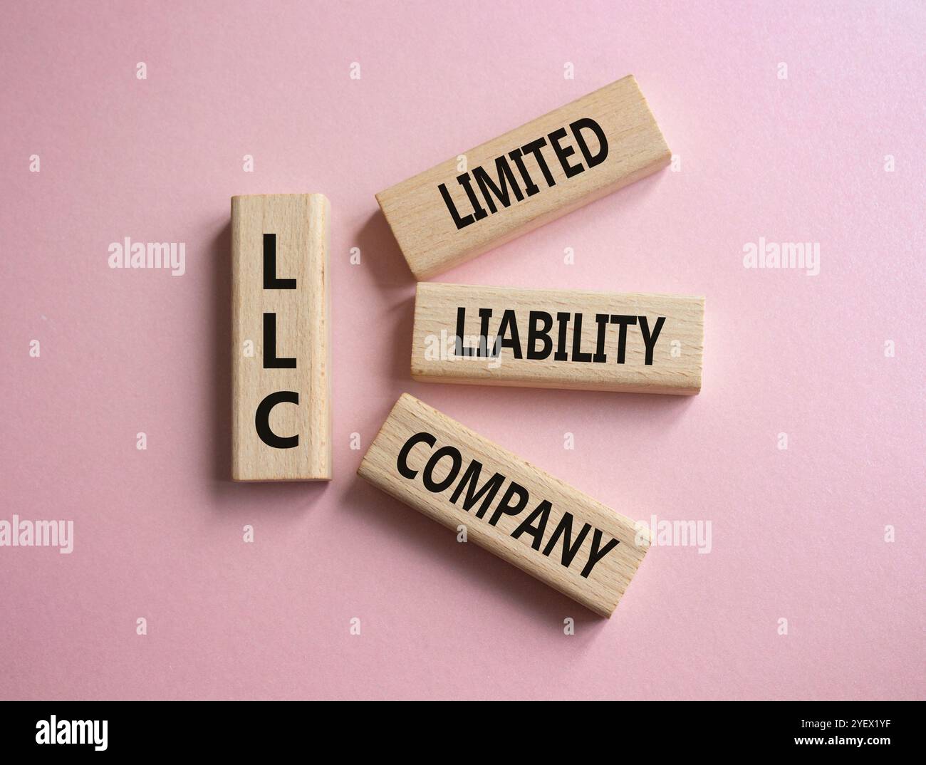 LLC - società a responsabilità limitata. Cubi in legno con parola LLC. Bellissimo sfondo rosa. Business e LLC. Copia spazio. Foto Stock