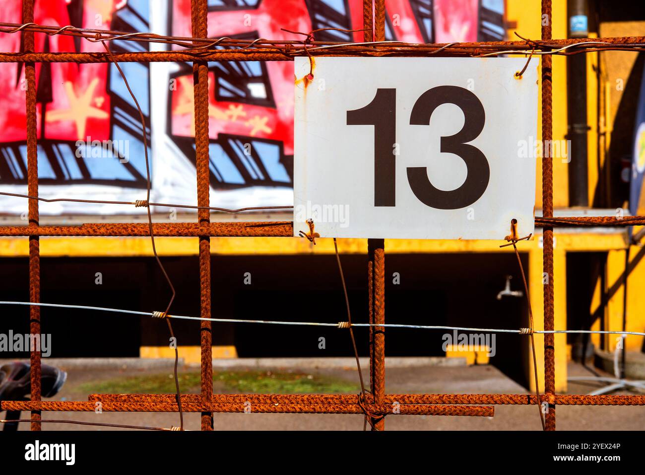 Cartello metallico con il numero 13 legato a ferro arrugginito con graffiti sullo sfondo Foto Stock
