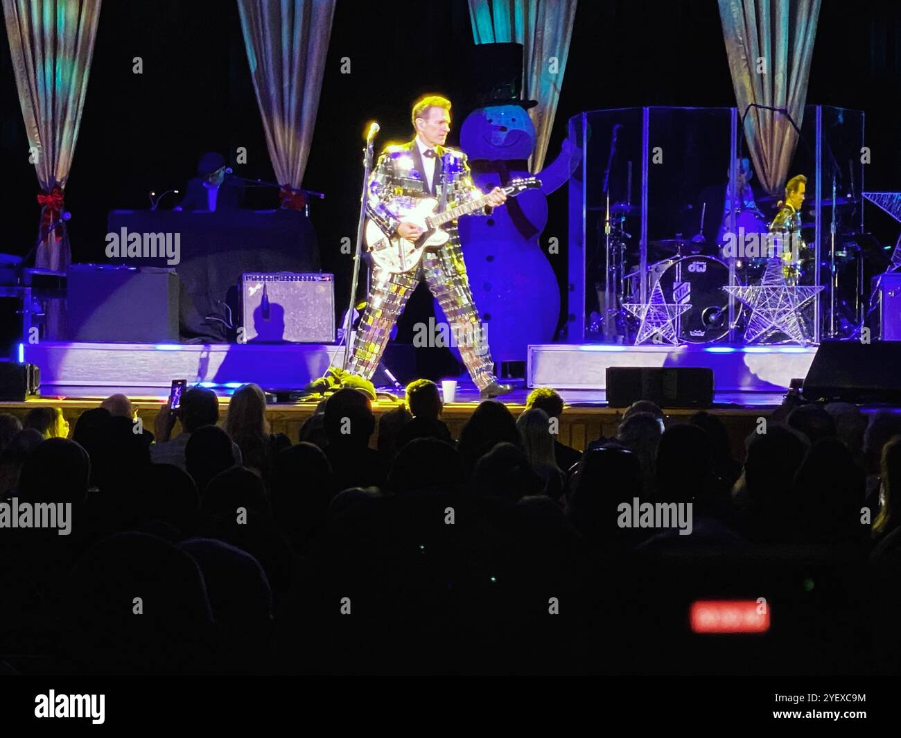 Chris Isaak, sul palco del Ryman Theatre di Nashville, Tennessee, novembre 2023, al "IT's Almost Christmas Tour". - Immagine stock catturata con smartphone