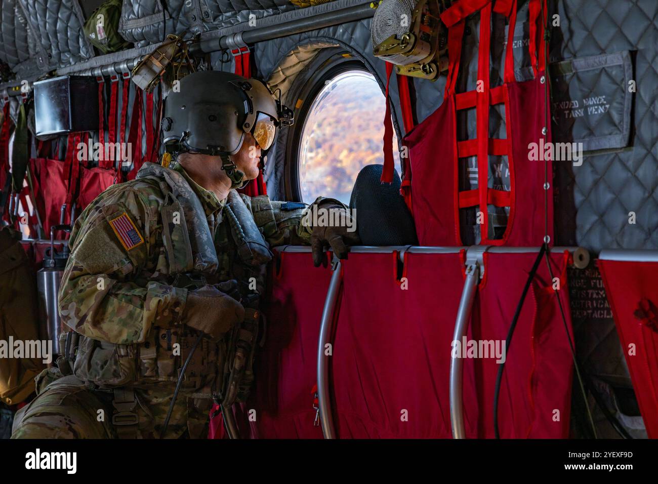 Adam Osip, un riparatore di elicotteri CH-47 assegnato al 2nd Battalion, 104th Aviation Regiment, guarda fuori dalla finestra di un elicottero da trasporto CH-47F Chinook mentre sorvola Berlino, Connecticut, 24 ottobre 2024. Osip è uno dei quaranta aviatori, vigili del fuoco e personale di supporto della Guardia Nazionale del Connecticut mobilitati per combattere il fuoco che ha colpito Lamentation Mountain. (Foto U.S. Army del sergente Matthew Lucibello) Foto Stock