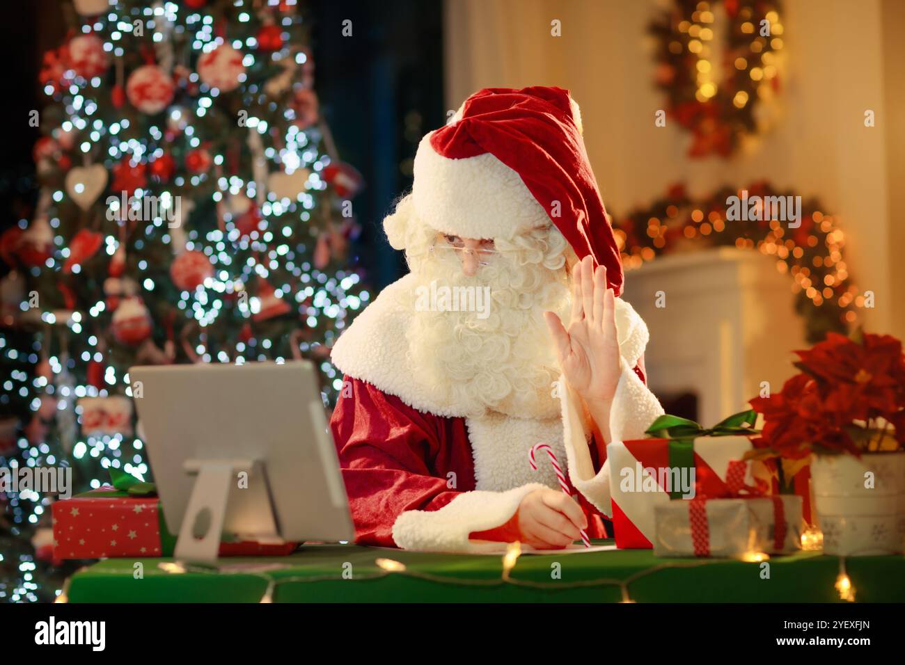 Videochiamata il giorno di Natale. La famiglia al cappello di Babbo Natale organizza una conferenza online alla vigilia di Natale. Babbo Natale che guarda la lista dei desideri dei bambini. Connessione con la famiglia Foto Stock