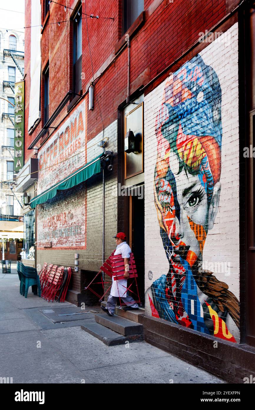 Colorato murale di audrey hepburn su un muro di mattoni in via dei gelsi, Little italy New york, persone che camminano in primo piano e un idrante del fuoco Foto Stock