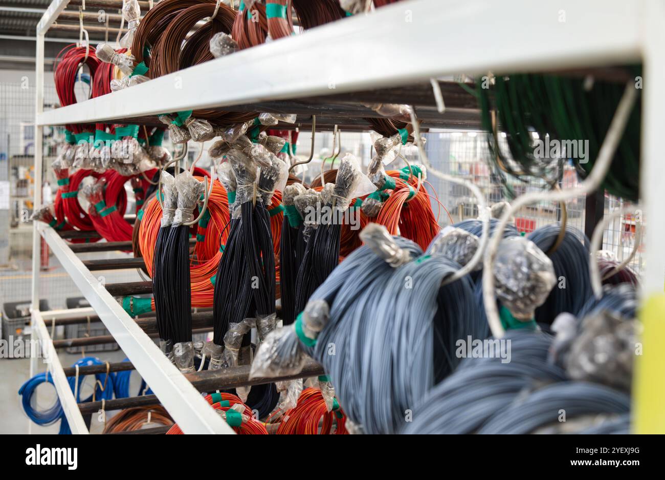 fabbrica di imbracature elettriche per auto, bobine di filo e perni utilizzati industrialmente nelle imbracature per auto, sospese su scaffali di un moderno impianto industriale Foto Stock