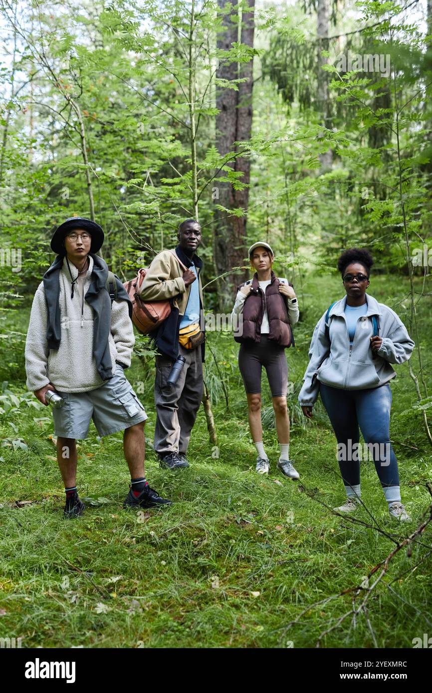 Gruppo multietnico di turisti che si trovano all'aperto sul sentiero della foresta e guardano la macchina fotografica mentre camminano insieme Foto Stock
