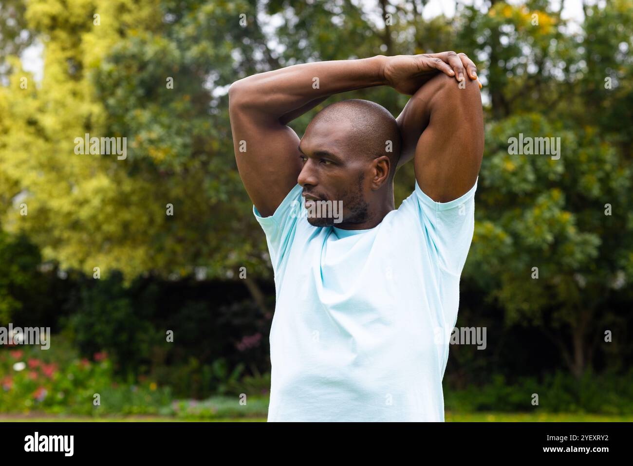 uomo afroamericano che allunga le braccia all'aperto nel parco, concentrandosi sul fitness e il benessere Foto Stock