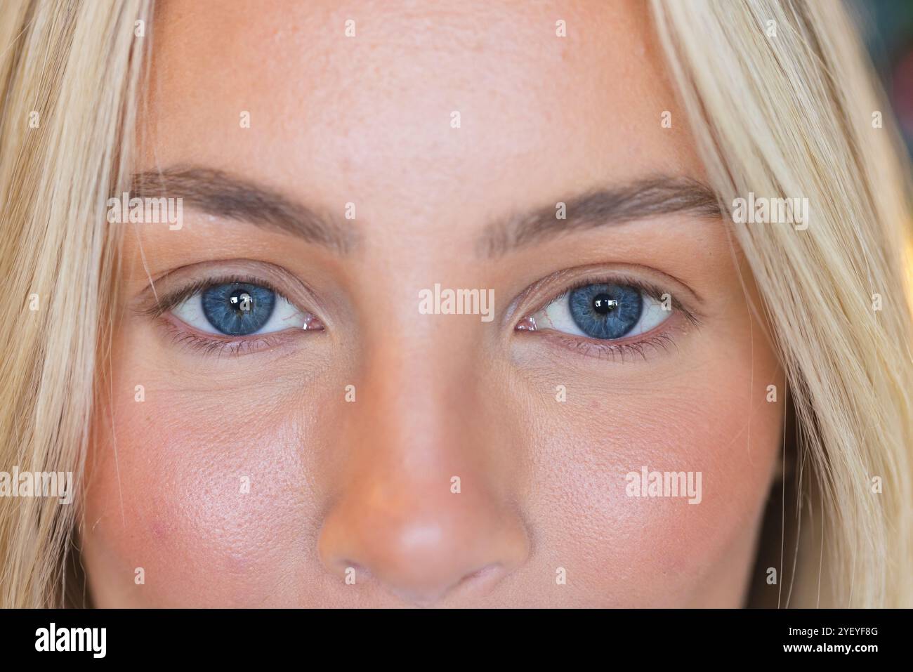 Primo piano degli occhi blu della donna e dei capelli biondi, che mostrano la bellezza naturale, a casa Foto Stock