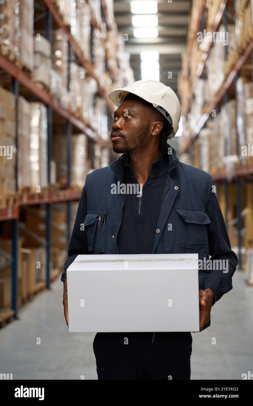 Addetto al magazzino che trasporta una scatola nel centro logistico Foto Stock