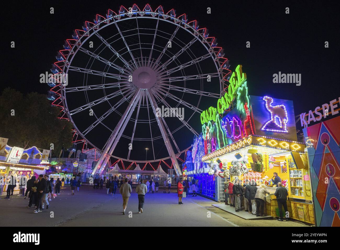 Una vivace fiera di notte con una ruota panoramica illuminata e negozi pieni di gente, Cannstatter Wasen, festival popolare, Bad Cannstatt, Stoccarda, Baden Foto Stock