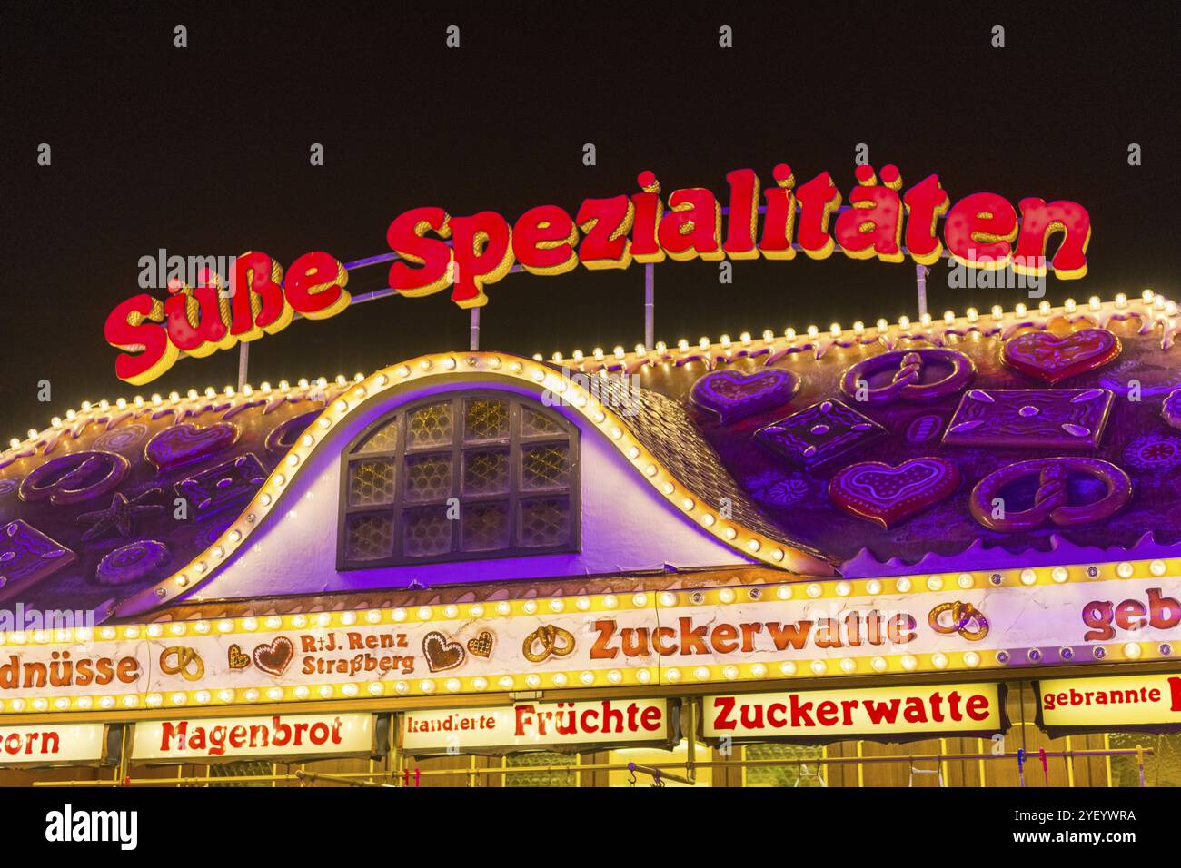 Caramelle inondate di luce in un parco divertimenti di notte, decorate con prelibatezze tradizionali, Cannstatter Wasen, festival folk, Bad Cannstatt, Stoccarda, B Foto Stock