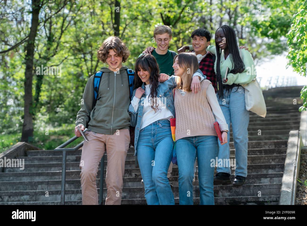 Gli studenti sono felici e diversi mentre scendono le scale dell'università. Un momento di amicizia genuina che mostra autentiche connessioni tra il multiculturale Foto Stock